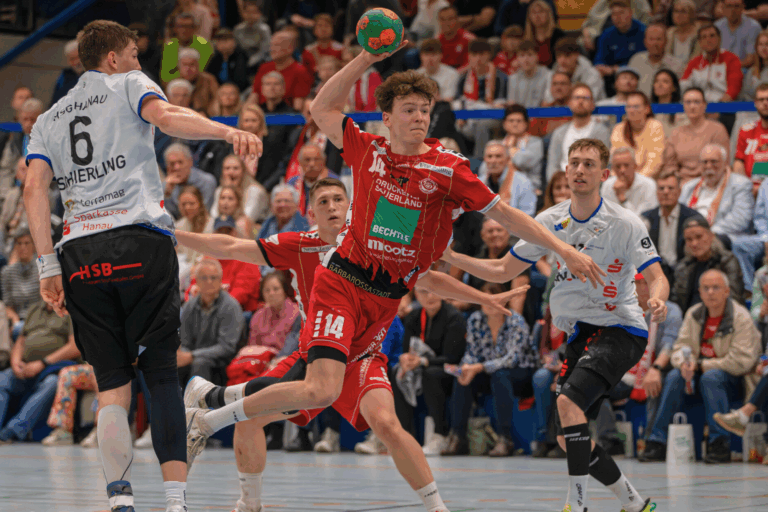 Hölle Süd kocht: TV Gelnhausen feiert Derbysieg gegen Hanau vor Rekordkulisse Was für ein Abend in der Rudi-Lechleidner-Halle! Vor atemberaubender Kulisse hat der TV Gelnhausen das mit Spannung erwartete Main-Kinzig-Derby gegen die HSG Hanau mit 34:28 (17:13) für sich entschieden. 1.600 begeisterte Zuschauer, eine emotionale Gedenkaktion für den verstorbenen Ex-Spieler Tim Altscher und ein bärenstarker Auftritt auf dem Feld machten diesen Abend zu einem der Höhepunkte der Saison. Schon vor dem Anpfiff lag eine ganz besondere Atmosphäre in der Luft: Beim exklusiven Netzwerkevent „SPORT meets BUSINESS“ versammelten sich rund 250 Gäste aus Wirtschaft, Politik und Sport, bevor sie sich gemeinsam mit den Fans auf ein echtes Handballfest einstimmten. Die Zuschauer erlebten zudem eine besondere Einlaufshow: Erstmals erklang der neue Einlaufsong des TVG, eigens komponiert von der Gelnhäuser Band „DOPPELBOCK“ – eine mitreißende Hymne, die die Hall