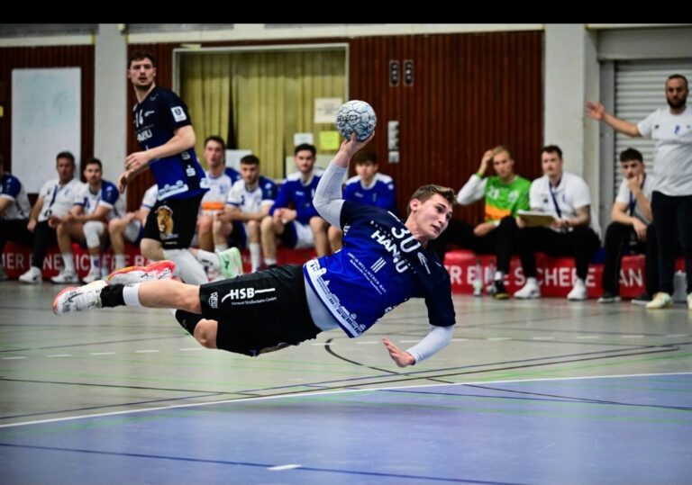 Auswärtsserie der HSG Hanau reißt in Köln Brüder-Grimm-Städter müssen sich in 3. Liga dem Longericher SC geschlagen geben Einen gebrauchten Abend erwischte Handball-Drittligist HSG Hanau am Samstag beim Longericher SC Köln. Nach zuletzt sechs ungeschlagenen Partien in der Fremde, verloren Bergold, Kleemann & Co. zum ersten Mal in der Saison 2025/26 in der 3. Liga Süd-West ein Auswärtsspiel. Beim 23:34 (10:14) schaffte es die HSG-Sieben nicht, an ihre spielstarke Leistung aus dem Derby gegen Münster anzuknüpfen. Dabei haderte das Team vor allem mit seiner Chancenverwertung und einer schwachen Phase nach dem Beginn der zweiten Halbzeit. „Wir sind mit hohen Erwartungen nach Köln gefahren und jetzt ist unsere Auswärtsserie gerissen, obwohl es eigentlich 45 Minuten lang nicht danach aussah“, äußerte sich HSG-Chefcoach Axel Spandau nach der Begegnung enttäuscht. Eine erfreuliche Nachricht: Bei der HSG gab Dennis Gerst (3 Tore) sein Comeback.